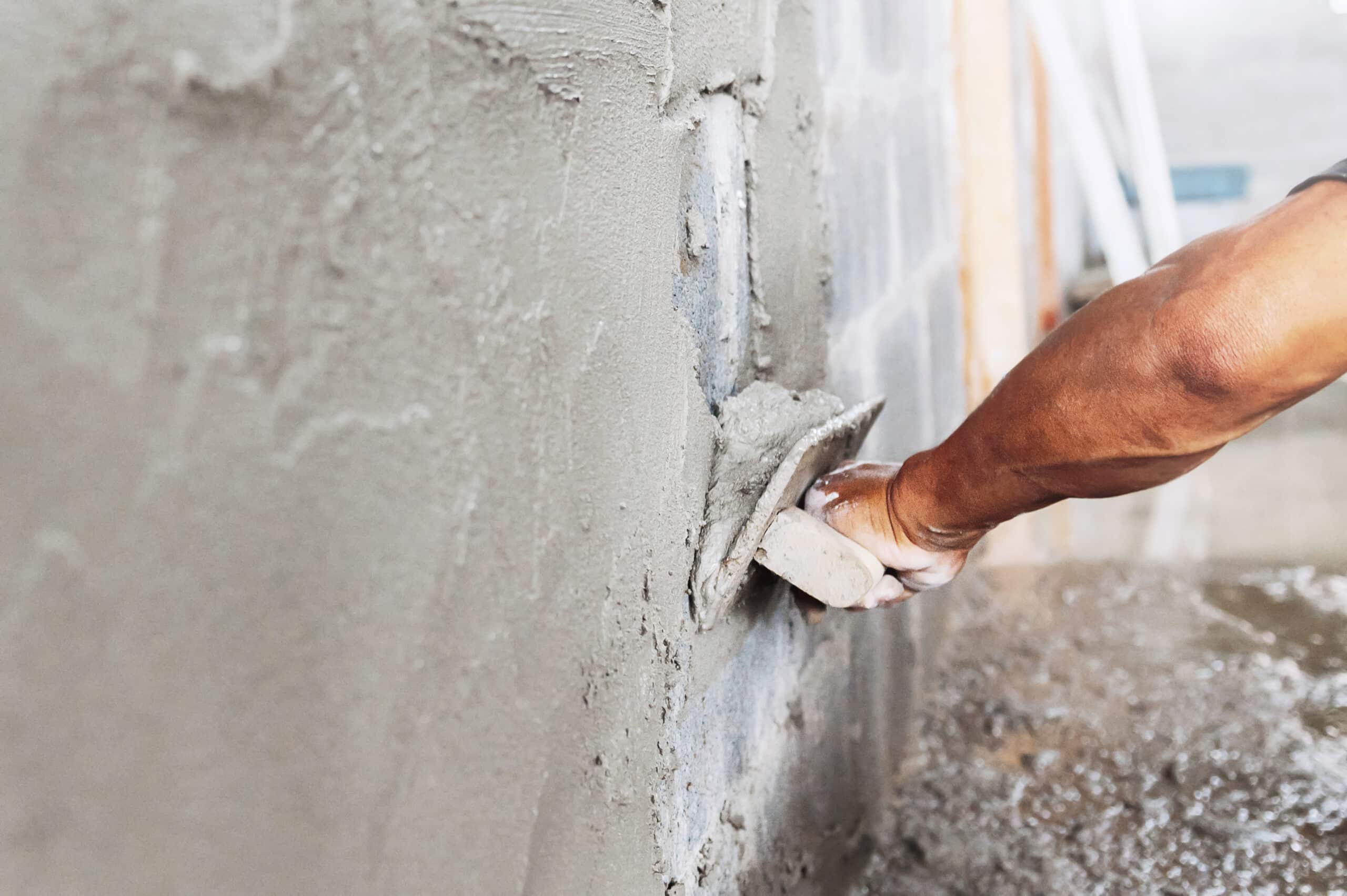 close up of workers hand plastering cement on wall